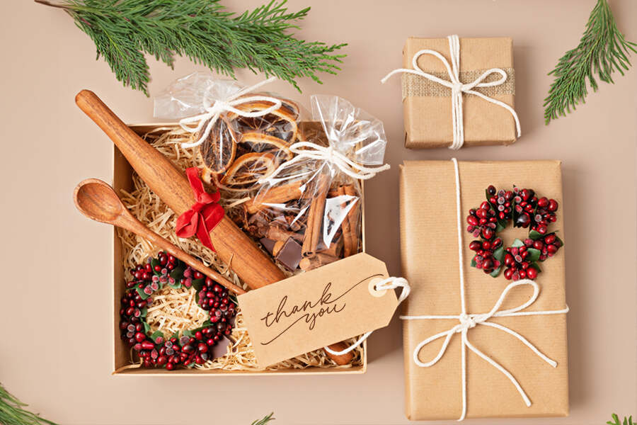 A festive gift box filled with cookies, a wooden spoon, and a gift tag, promoting sustainable corporate chocolate gifting