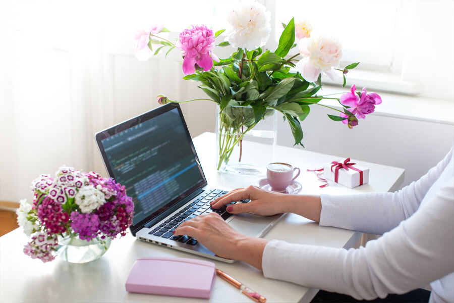 A woman types on her laptop at a desk, embodying the spirit of productivity and celebration for Mother's Day at work