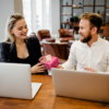 A man and woman at a table with laptops, celebrating Administrative Professionals Day with chocolate gifts