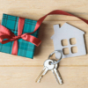 A house key rests beside a gift box adorned with a ribbon, symbolizing thoughtful real estate closing gifts for clients