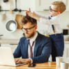 A man and a child celebrate Father's Day at work, sitting together at a table with a laptop open between them