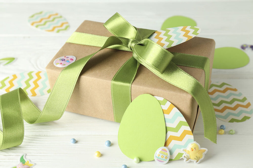 Easter corporate holiday gift wrapped with a festive green bow and surrounded by Easter egg decorations.