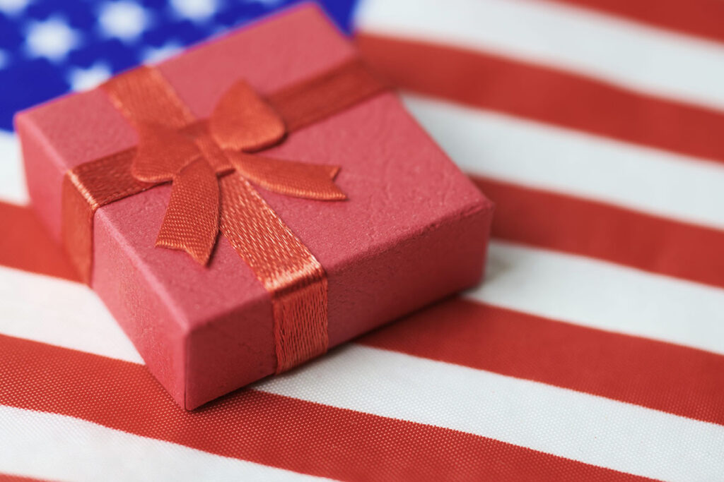 July 4th Independence Day holiday gift for clients wrapped in a red box and bow atop an American Flag