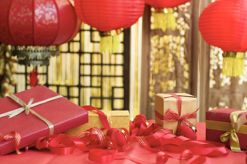 Lunar new year business gifts for clients surrounded by red and gold traditional decorations.