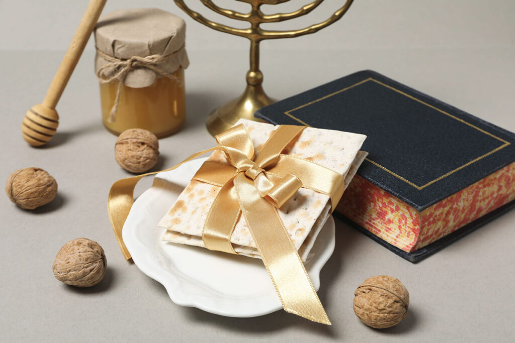 Ras Hashana holiday gift surrounded by honey, walnuts, and religious text and decorations.