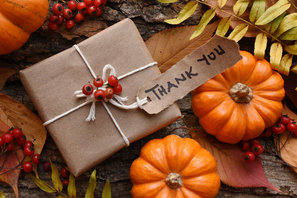 Thanksgiving holiday business gift surrounded by pumpkins and autumn decorations